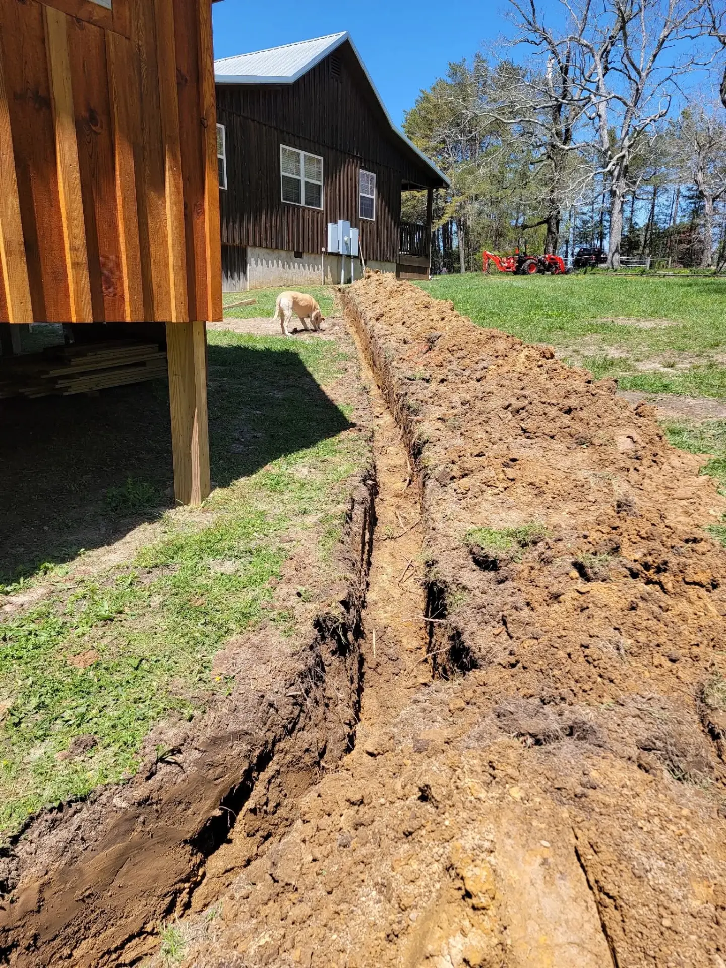 Utility trench dug alongside a cabin on stilts