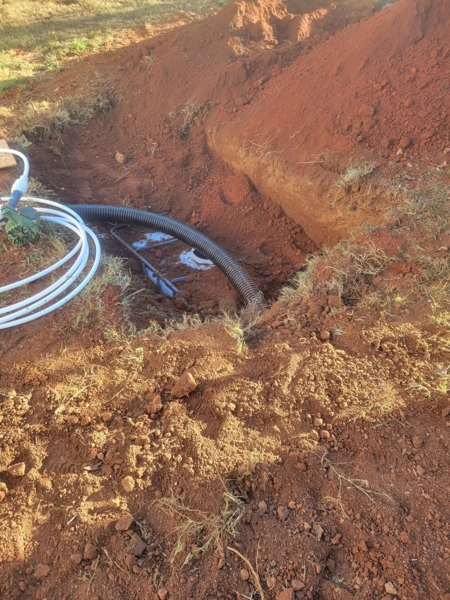 Drain pipe and sump basin set in a red clay excavation