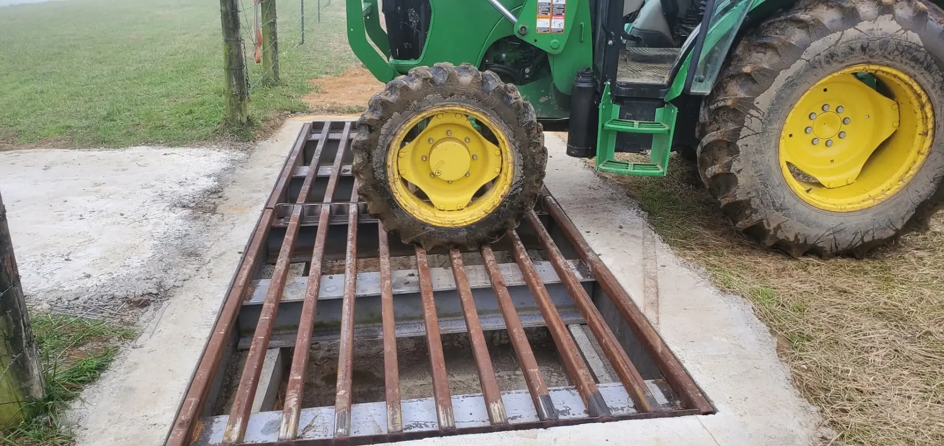 Steel cattle guard set in a concrete base at a farm gate