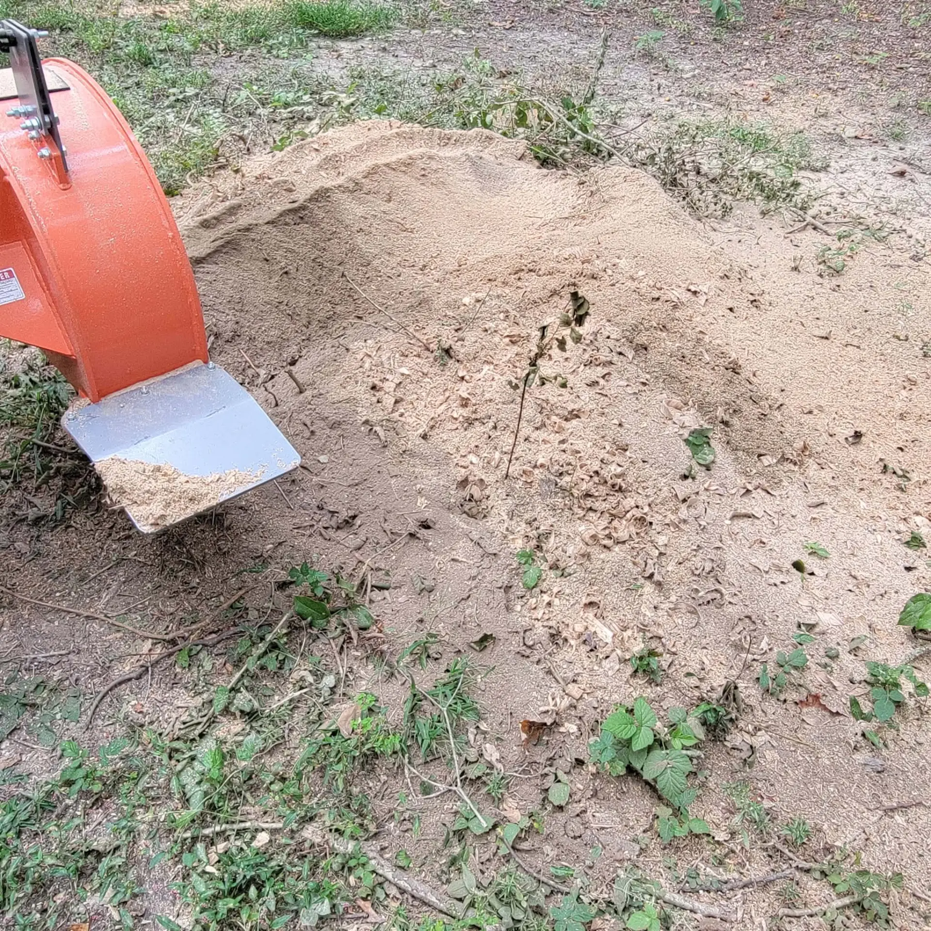 Stump grinder beside a pile of fresh wood chips