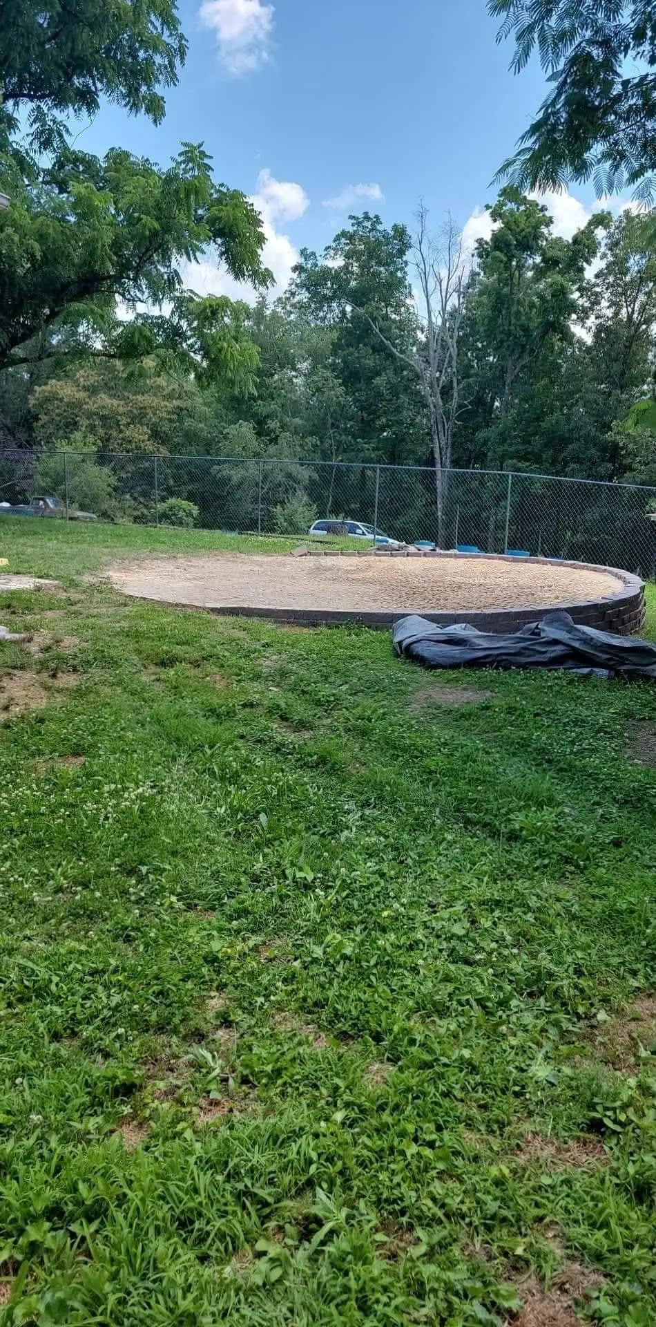 Round leveled sand pad with a block retaining edge in a backyard