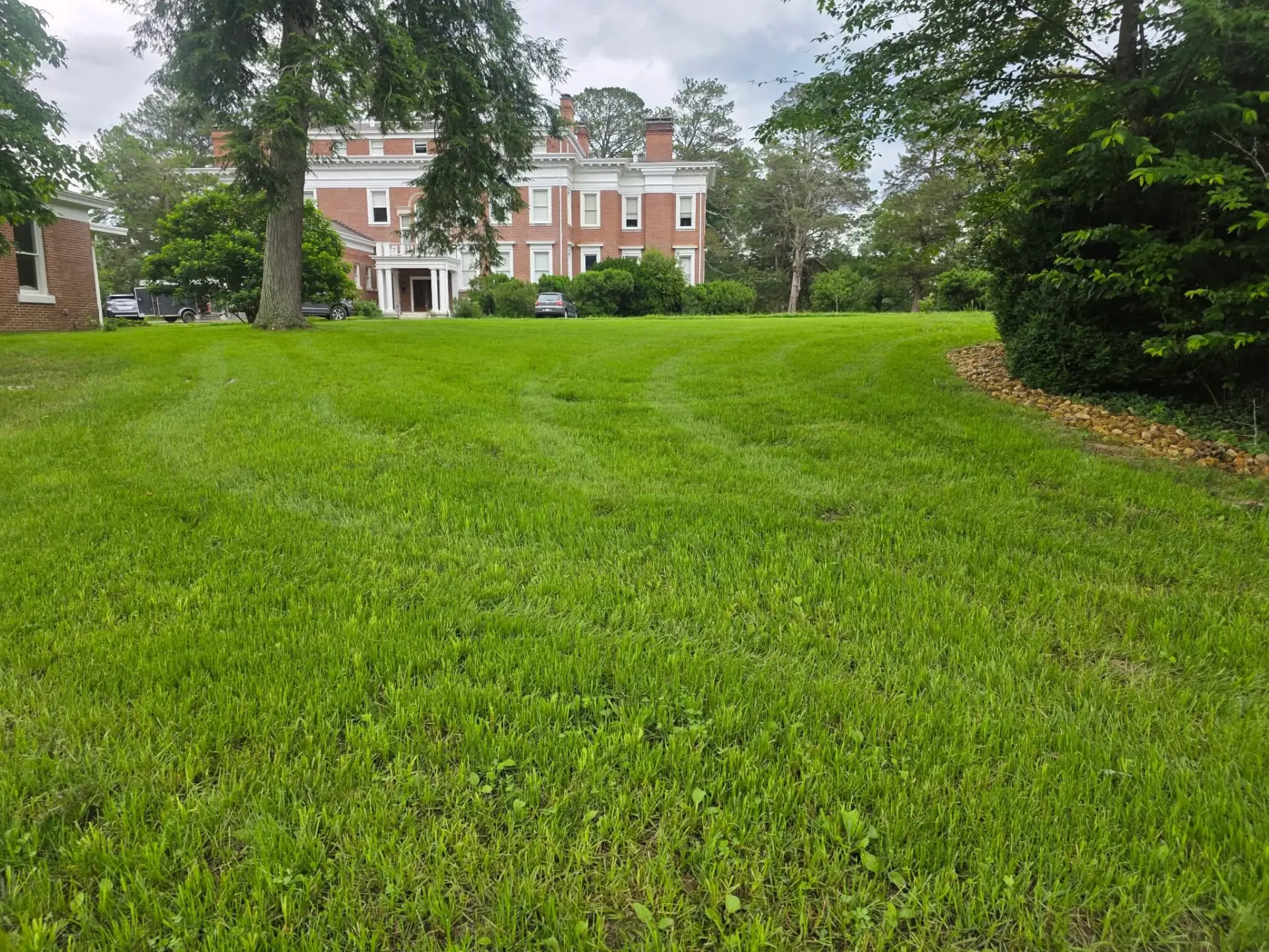Thick green lawn in front of a large brick home