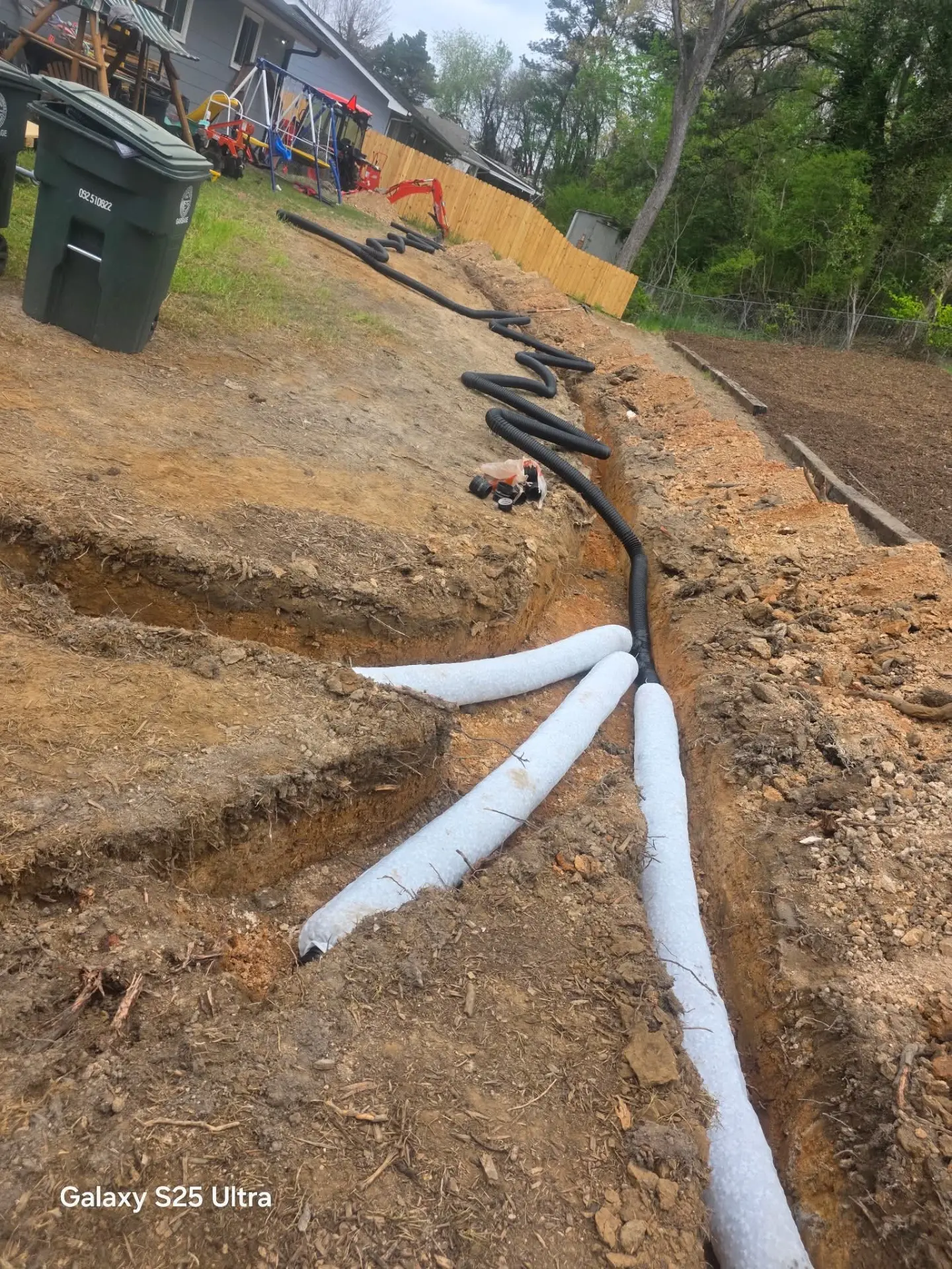 French drain trench with perforated drain pipe installed in a backyard