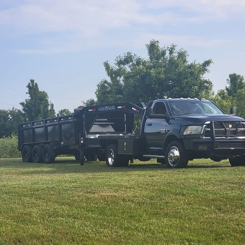 Walden Farms dump truck and gooseneck dump trailer parked in a field