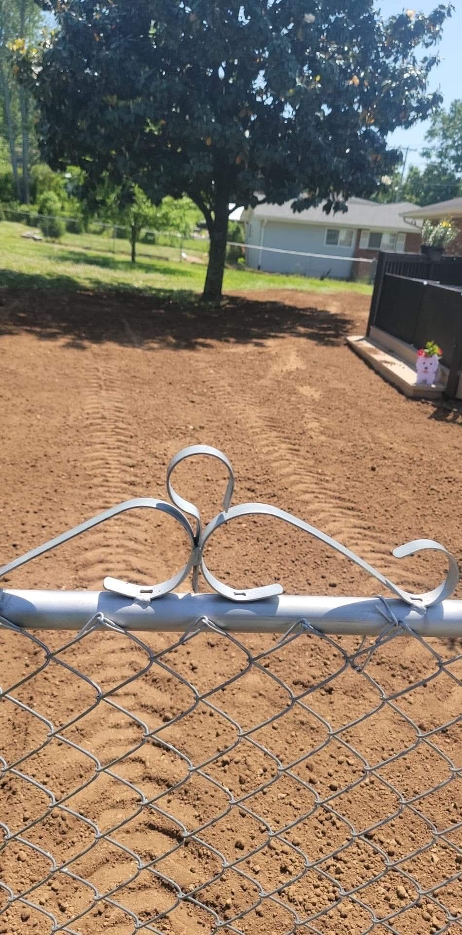 Freshly graded smooth dirt backyard seen through a chain link fence