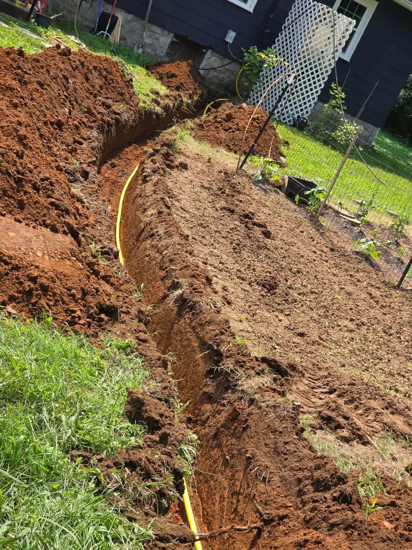 Yellow gas line laid in a trench along a backyard garden